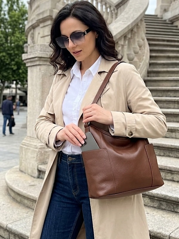 Mulher pegando celular no bolsos externo da bolsa hobo em couro legitimo marrom