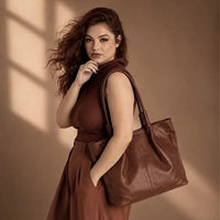 Mulher usando a bolsa de ombro tote marrom, destacando o caimento elegante com o vão livre de 30cm da alça.