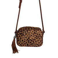 Close-uo frontal da bolsa tiracolo de couro ressaltando o acabamento premium e a textura do pelo natural.