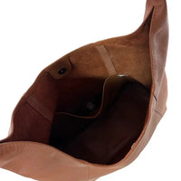 Interior da bolsa hobo sem forro mostrando o bolso organizador aberto e o verso natural do couro legítimo.