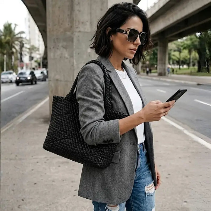 Mulher usando a bolsa shopper treesê preto com jeans e blaser cinza