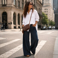 Mulher com jeans e camisão branco usando a bolsa transversal de onça ajustada na altura do quadril, destacando o caimento.
