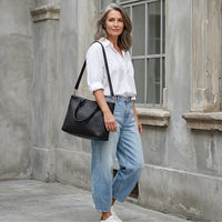 Look Jeans e Camisa Branca Usando a Bolsa shopper feminina preta com textura tressê em couro vegano e alças de ombro.