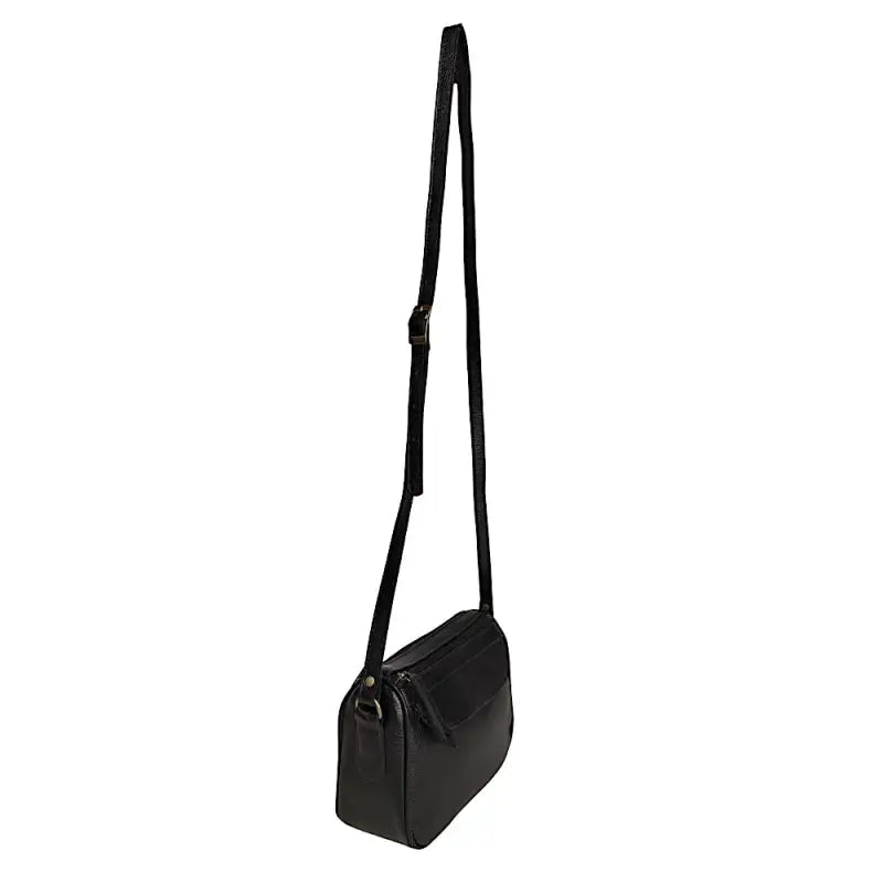Mulher de blazer com a bolsa crossbody preta apoiada ao lado no chão.