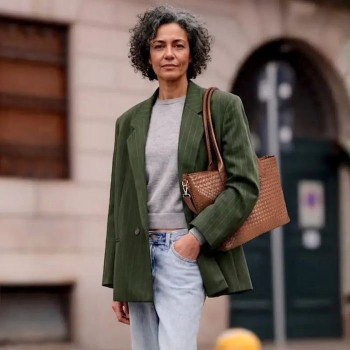 Mulher com Look Jeans e Blaser Verde Usando a Bolsa shopper feminina caramelo com textura tressê